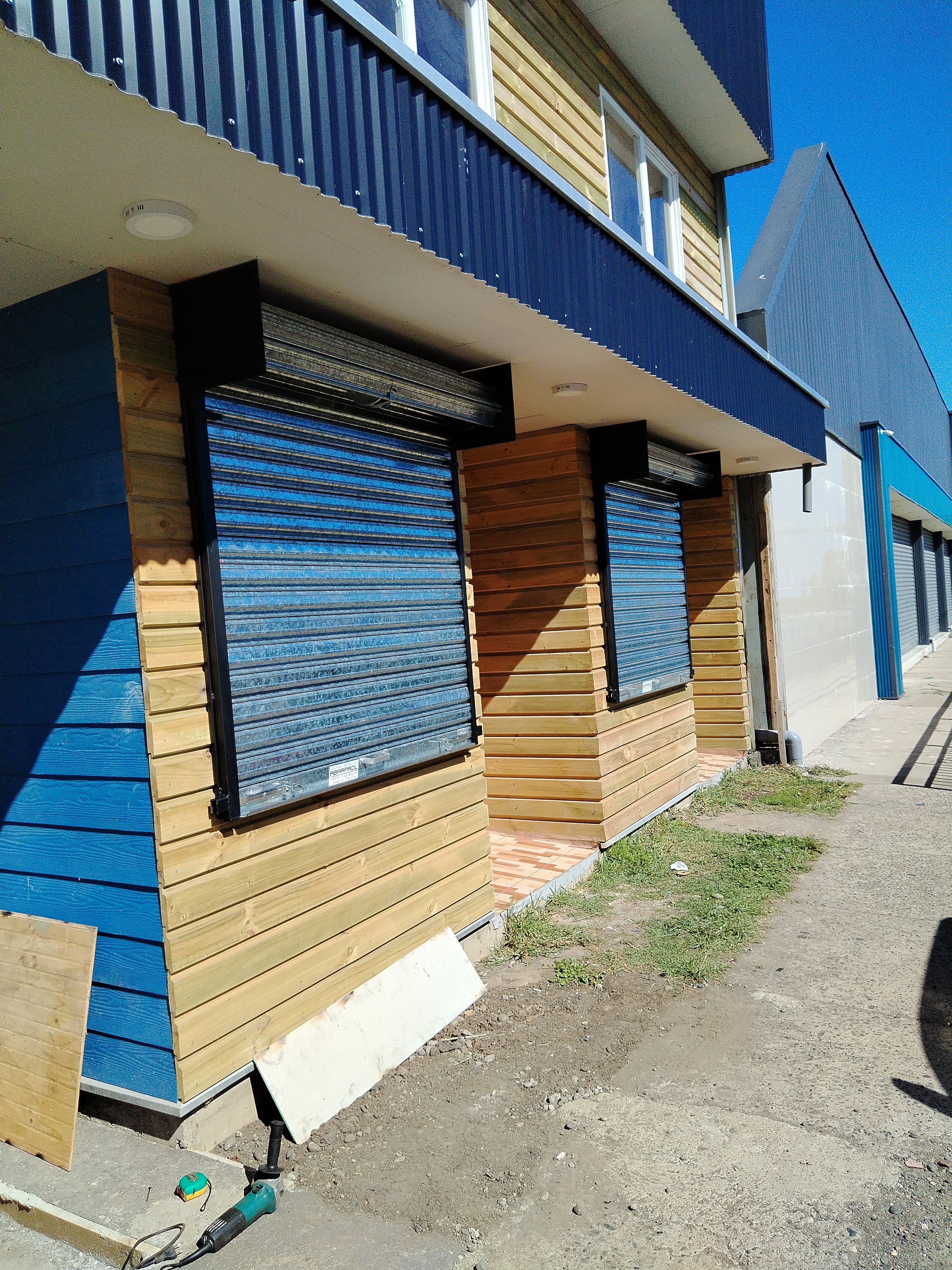 Cortinas metálicas motorizadas en local comercial con fachada de madera